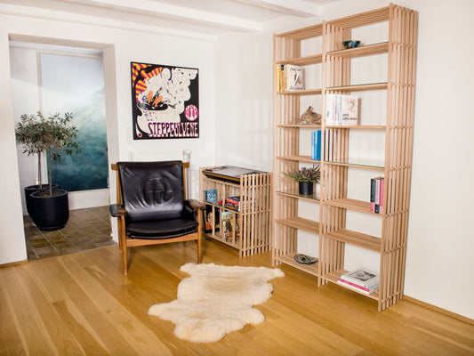 Stue med to tremmereoler. Den ene er to-delt med 15 rum. Man ser en stereo bænk samt en lænestol i læder.